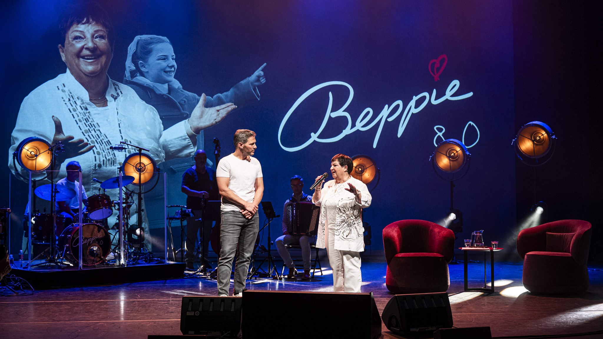 Beppie Kraft op het podium bij Beppie 8.0, met liveband en beelden uit haar leven